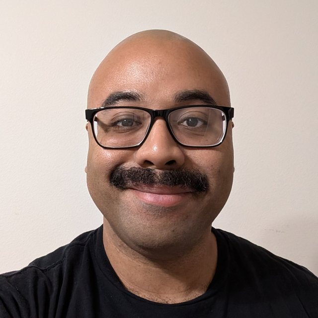 Cortney Martin, in glasses and a black T-shirt, smiling.